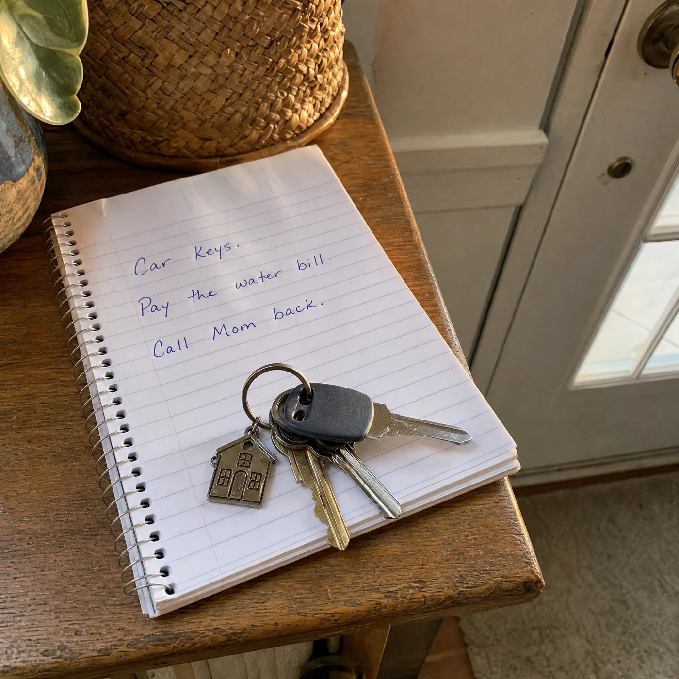 Notepad by the front door with handwritten reminders: car keys, pay the water bill, call Mom back