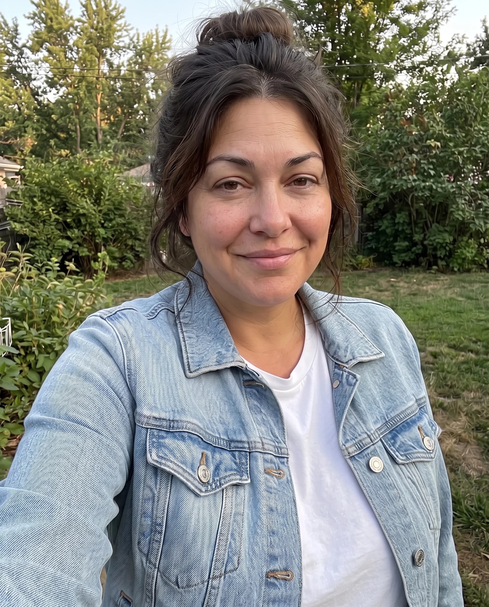 A woman smiling outdoors in natural sunlight, relaxed and free
