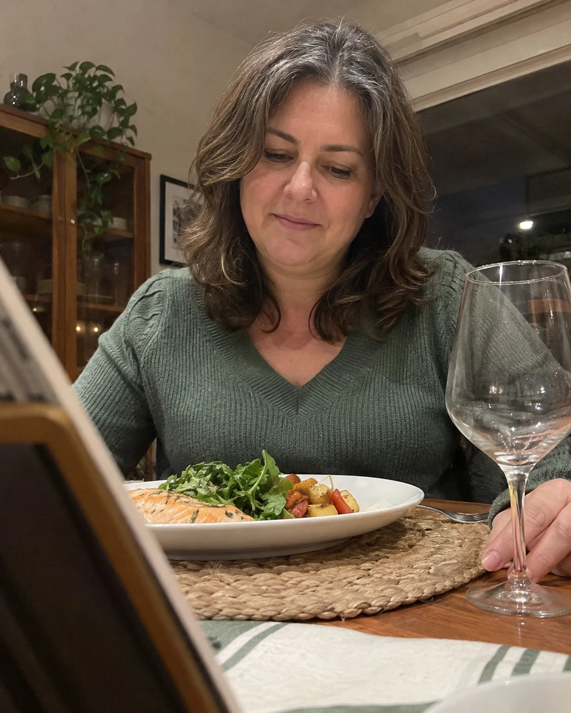 Woman sitting at the dinner table near an empty wine glass