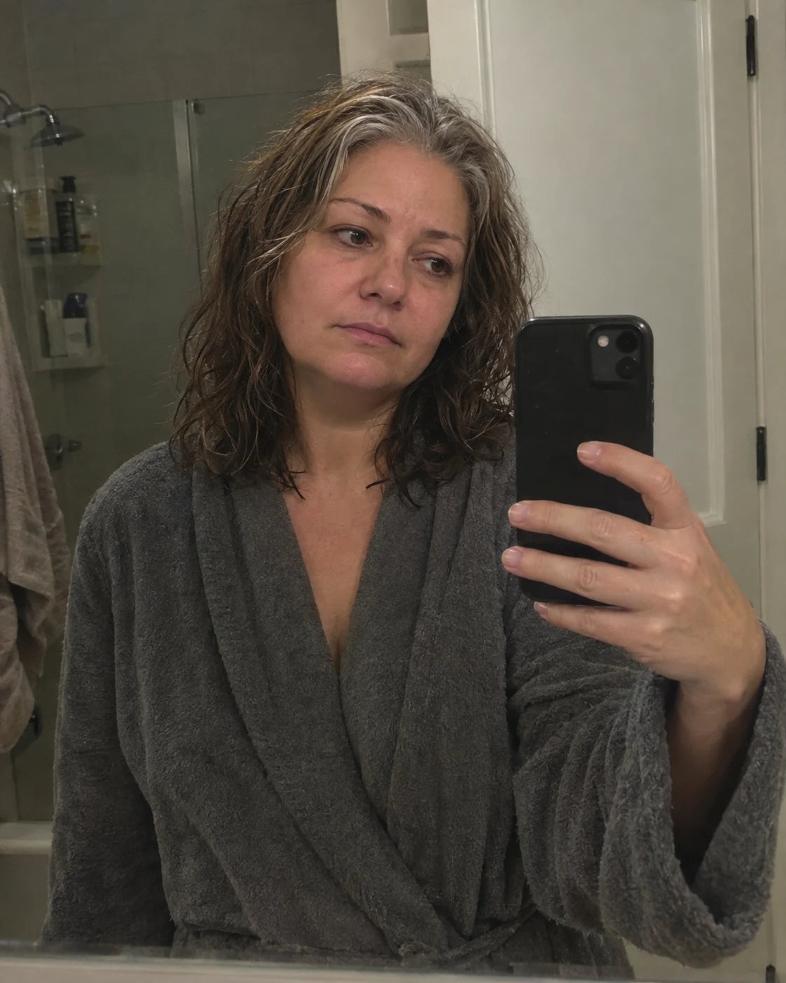 Woman looking at her tired reflection in a bathroom mirror at night