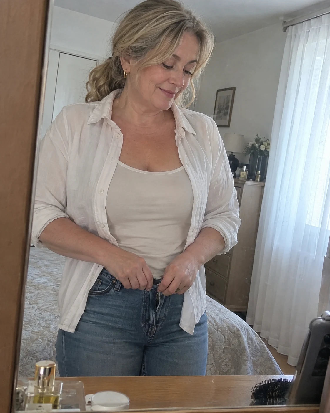 Woman fastening her jeans comfortably in soft morning light