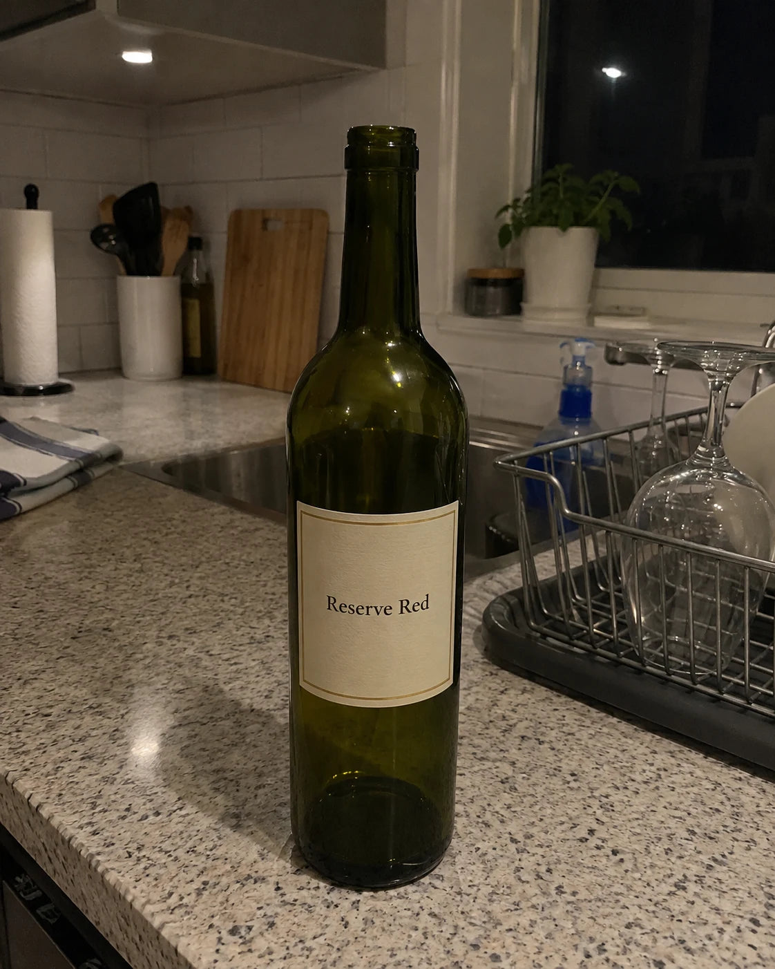 Empty wine bottle alone on a kitchen counter at night