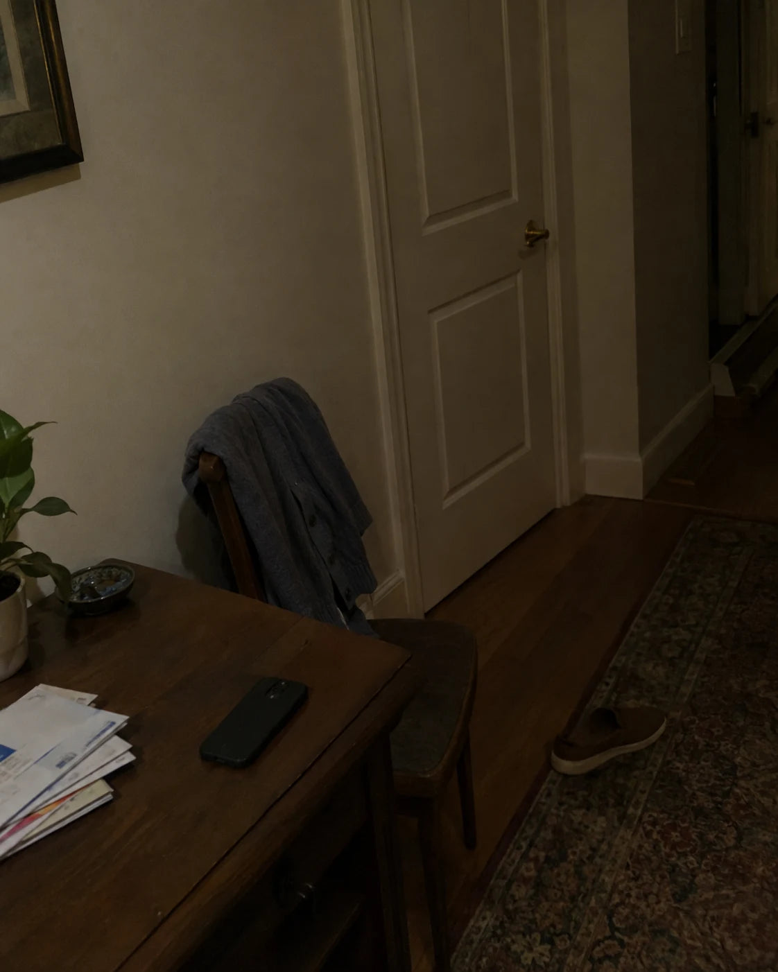 A closed bedroom door in a quiet hallway, a phone face-down on the table nearby
